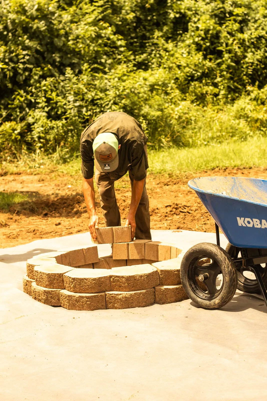 A worker placing a block in a circular fire pit during construction