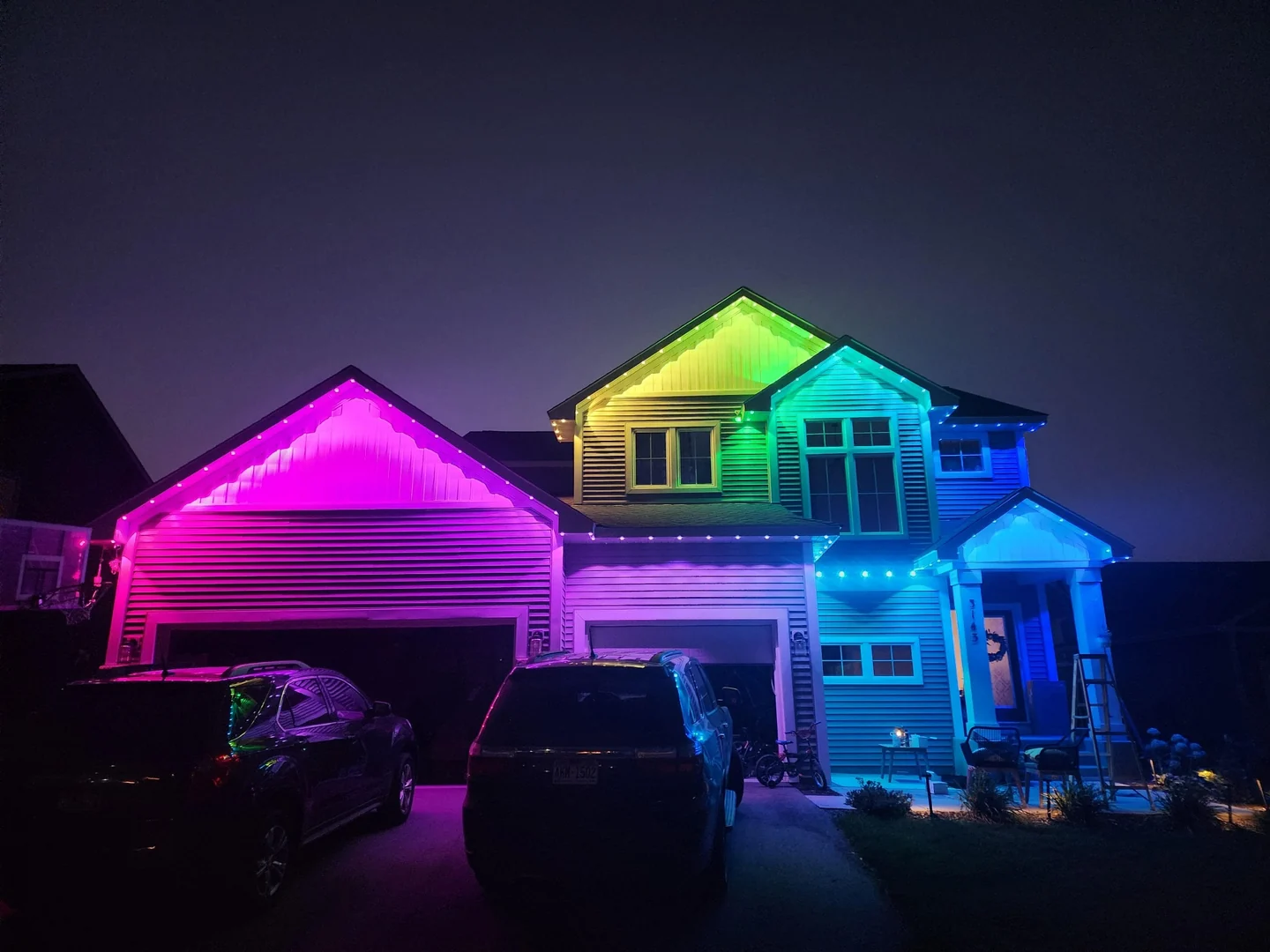 Permanent multicolor roofline lighting illuminating a two-story home at night